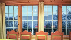 Une pièce dotée de grandes fenêtres, de meubles en bois et offrant une vue sur les montagnes.
