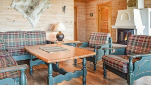 Un intérieur de chalet chaleureux, avec des meubles à motifs écossais, une table en bois et une cheminée.
