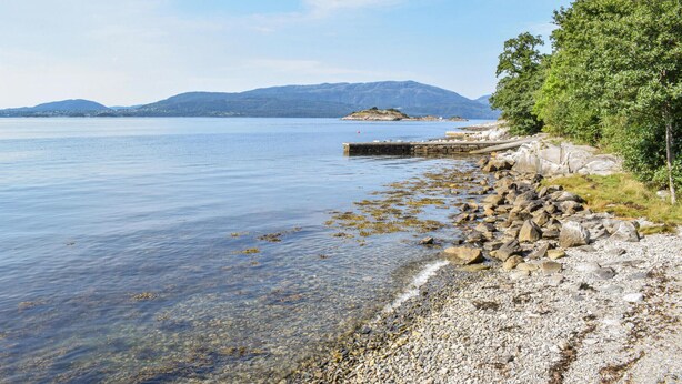 Un lac aux eaux limpides, bordé d’une rive rocheuse et doté d’une jetée qui s’avance dans l’eau.