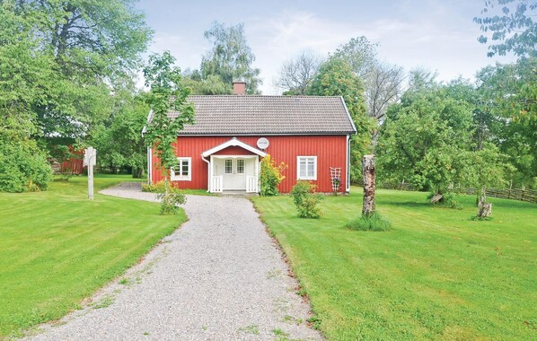 Een rode houten woning met een witte deur en een grindpad er naartoe.