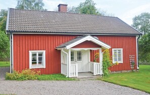 Een rode houten woning met een witte veranda en een oprit van grind.