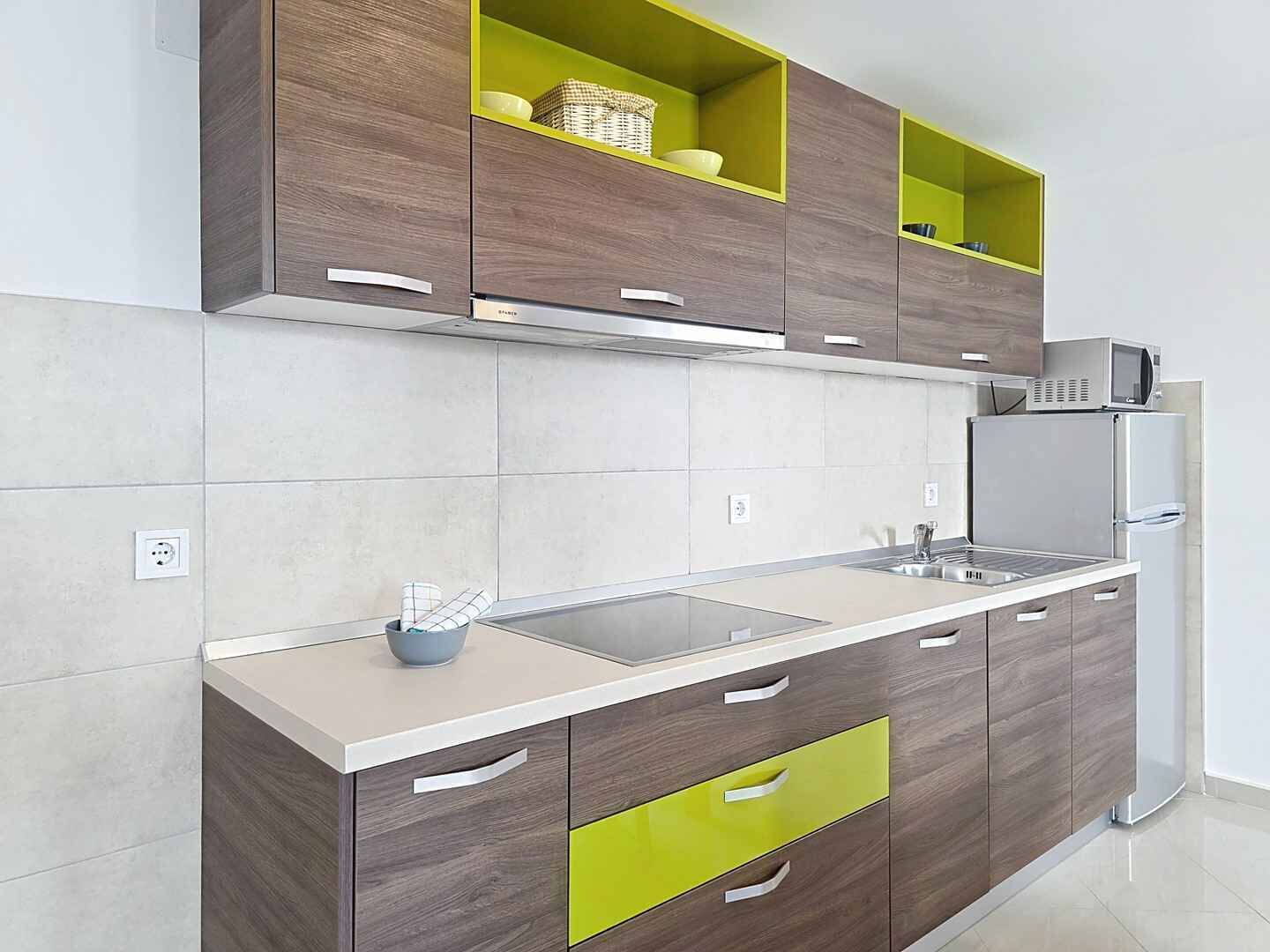 Cozinha moderna com armários cinza, bancada branca e micro-ondas embutido.