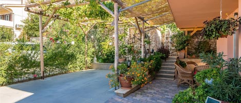 A covered outdoor area with a pergola, potted plants, and a chalkboard sign.