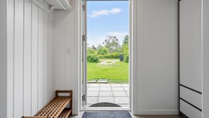 Ein Durchgang zu einer Terrasse mit einer Bank und Blick auf eine Rasenfläche.
