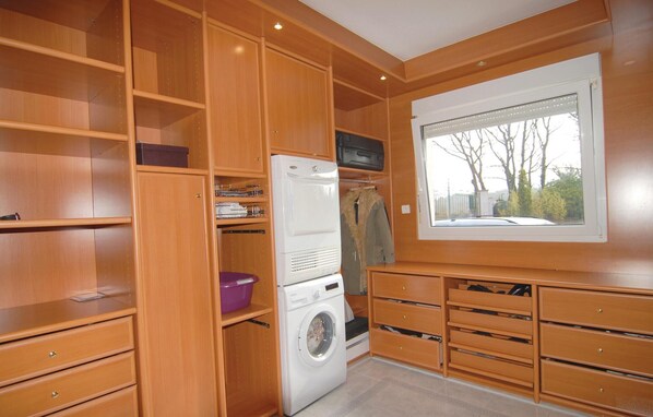 A compact, well-organized laundry room with built-in shelves, a washing machine, and a window providing a view of the outside. - Pet friendly home in Trets (Trets)