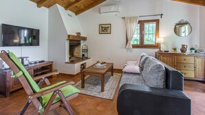 Una sala de estar acogedora con chimenea, un sofá, un televisor y un comedor.