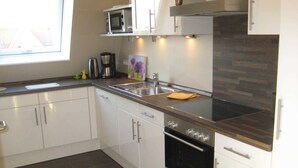 A modern kitchen with white cabinets, a stainless steel oven, a microwave, and a sink. - 4-room 205 Norderney 3Balk Spülm. 2Bäder (BC 5) - BUE - Appartementhaus Westwind (Büsum)