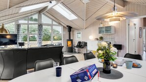 A modern kitchen with a built-in stove, a dining table with chairs, and a large window overlooking greenery. - Nice home in Rudkøbing with sauna (Rudkøbing)