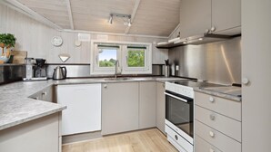 A modern kitchen with a built-in oven, a coffee machine, and a window with a view of greenery. - Nice home in Rudkøbing with sauna (Rudkøbing)