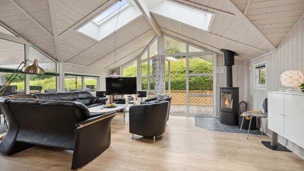 A spacious living area with a high ceiling, large windows, a fireplace, and modern furniture. - Nice home in Rudkøbing with sauna (Rudkøbing)