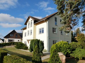 Une maison à deux étages avec une pelouse bien entretenue, un chemin et plusieurs arbres.