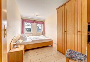 Une chambre à coucher avec un lit en bois, une table de chevet avec une lampe, une chaise et une armoire.