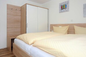 A bedroom with a bed, wooden wardrobe, and a painting on the wall.
