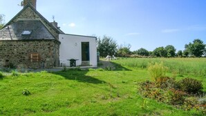 Una casa de piedra con fachada blanca, un porche pequeño y una puerta verde.