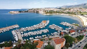 Un port de plaisance où sont amarrés de nombreux bateaux, entouré de bâtiments résidentiels et d’une ville côtière.