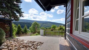 A patio with a stone pathway, wooden fence, and a view of a mountainous landscape. - Holiday home with stylish wooden furniture (Horní Maršov)