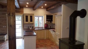 A kitchen with wooden beams, a central island, and a black stove. - Holiday home with stylish wooden furniture (Horní Maršov)