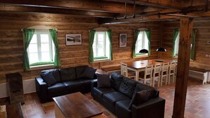 A cozy cabin interior with a black leather sofa, wooden dining table, and green curtains. - Holiday home with stylish wooden furniture (Horní Maršov)