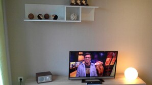 A television on a wooden TV stand with a remote control, a small speaker, and a decorative ball.