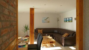 Un salon moderne avec un canapé en cuir marron, une table basse en bois et une table à manger pour quatre personnes.