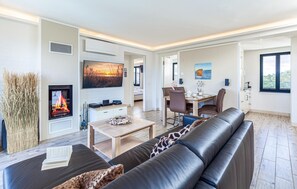 A modern living room with a fireplace, a dining area, and a view of the outdoors.