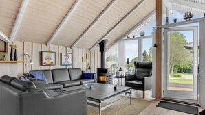 Una sala de estar moderna con chimenea, sofás de cuero y ventanas amplias con vistas al exterior.