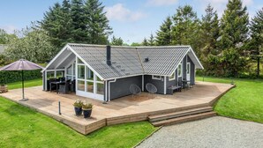 Una casa moderna con una amplia terraza, dos zonas de estar al aire libre y un porche cubierto.