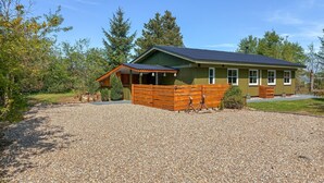 Een gelijkvloers huis met een grindpad, een houten omheining en een klein terras.