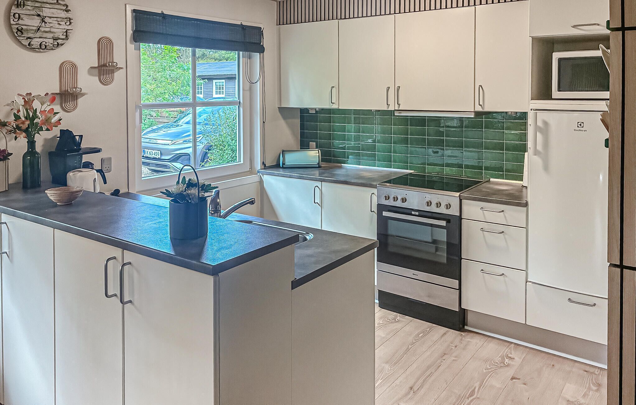 A modern kitchen with white cabinets, a black stove, and a green backsplash.