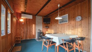 Een gezellig chalet-achtig vertrek met houten inrichting, een open haard, een eettafel met stoelen en een klok aan de muur.