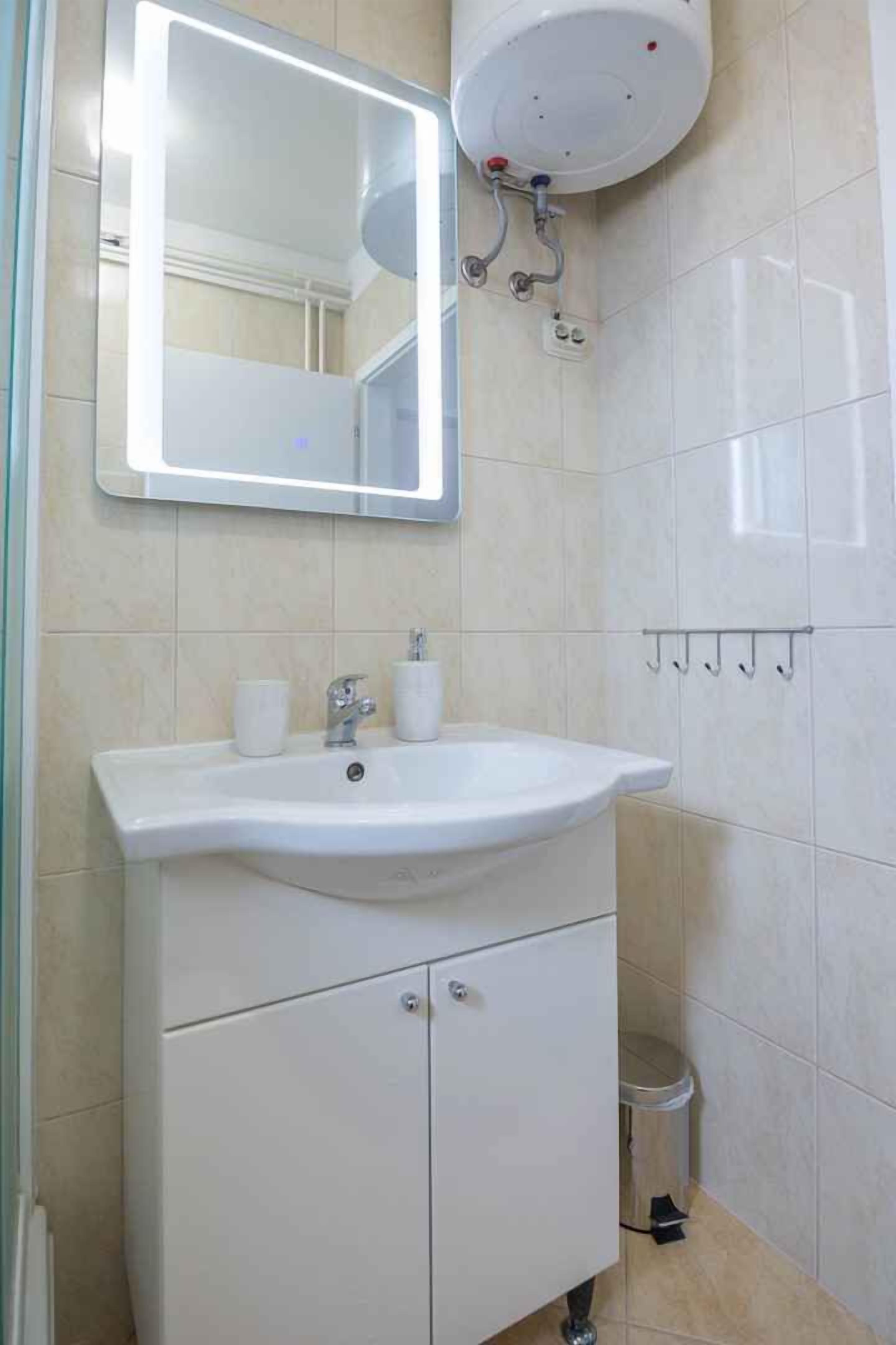 A bathroom with a white sink, mirror, and toilet.