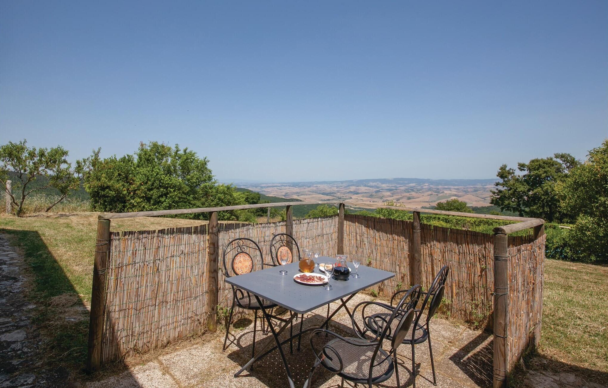 An outdoor dining area with a table and chairs, surrounded by a bamboo fence, overlooking a scenic landscape.