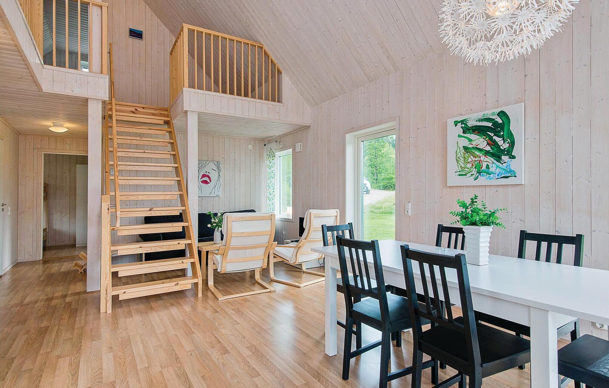 Ein geräumiger Essbereich mit hoher Decke, Holzboden und einer Treppe, die zu einer oberen Ebene führt.