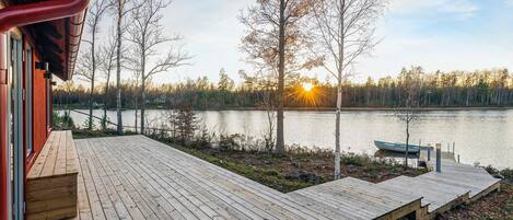 A wooden deck with a view of a lake and trees.