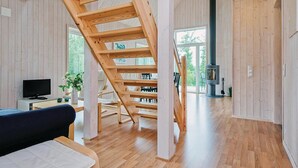 A modern interior with a wooden staircase, a fireplace, and a television in a cozy living area. - Stunning home in Holmsjö with kitchen (Holmsjö)