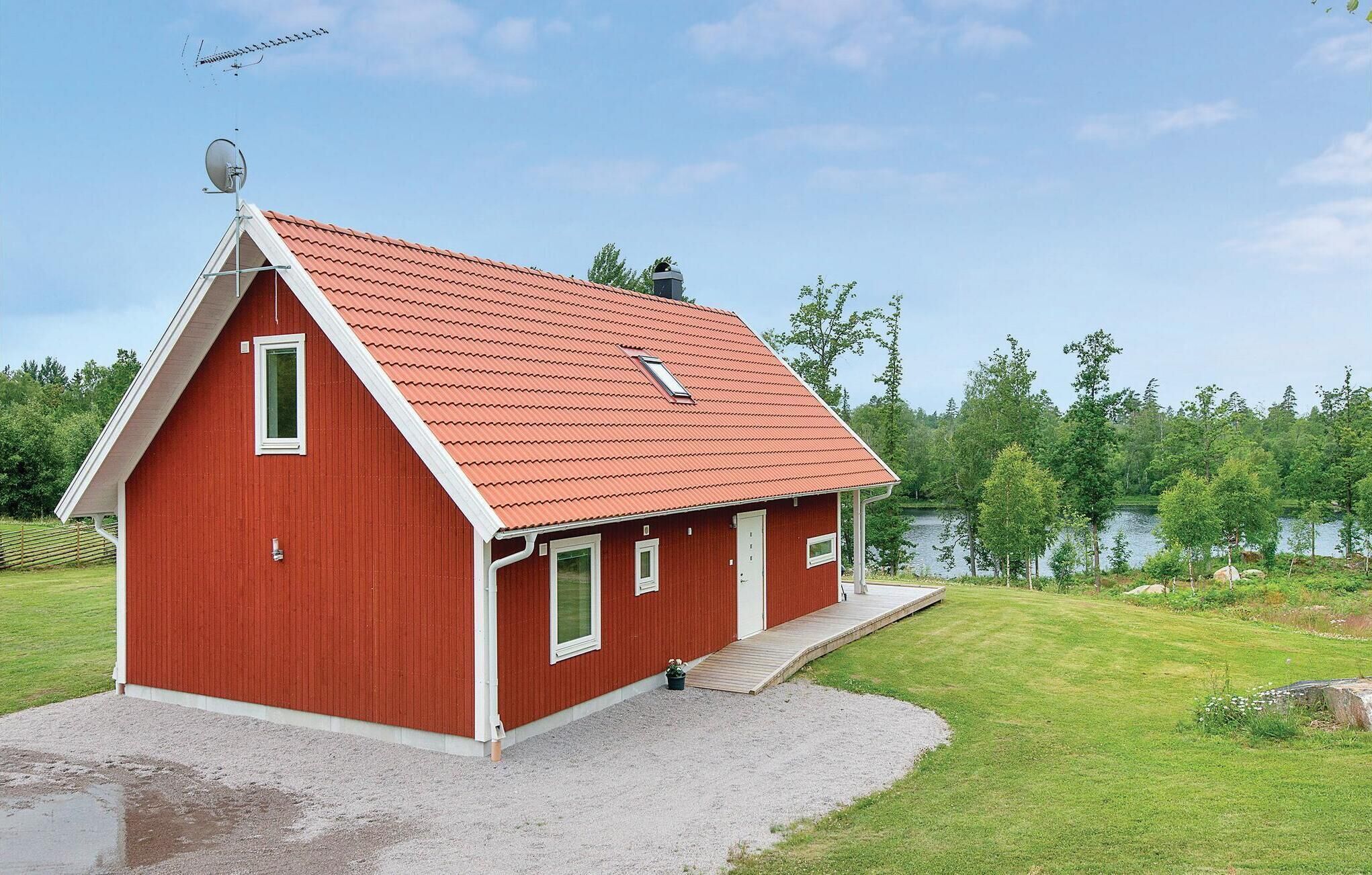 Ein rotes Bauernhaus mit geneigtem Dach, einer kleinen Veranda und einer Schotterauffahrt.