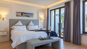 Habitación de hotel con una cama grande, lámparas de noche, un cuadro y vistas al exterior.