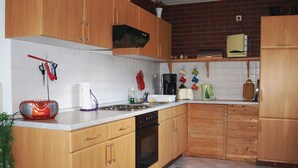 Une cuisine avec des meubles de rangement en bois, une cuisinière, un évier et divers ustensiles de cuisine.