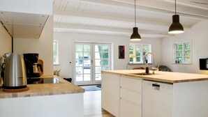Una cocina moderna con una isla central, iluminación colgante y vistas al exterior a través de un ventanal.