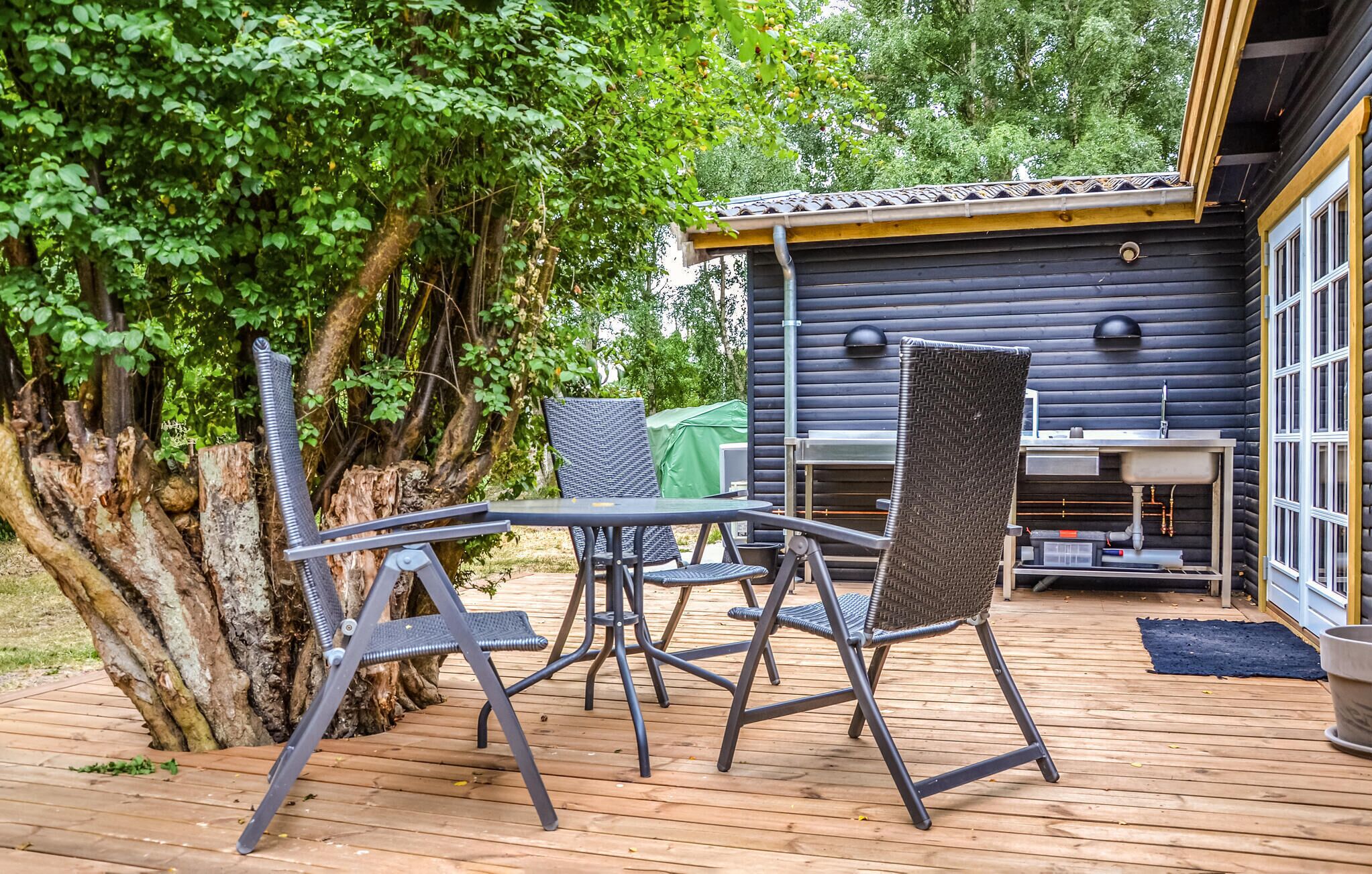 Eine Terrasse im Freien mit Tisch, Stühlen, einem Grill und Holzdeck.