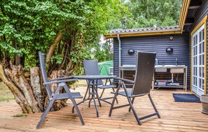 An outdoor deck with a table and chairs, a grill, and a wooden deck.