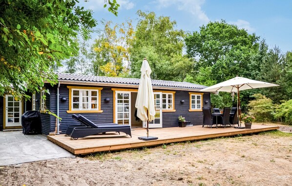A wooden cabin with a deck, outdoor seating, and a covered patio area.