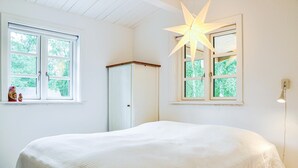 Un dormitorio con cama, dos ventanas, una lámpara colgante en forma de estrella y una lámpara de pared.