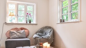 Una habitación acogedora con un sofá gris, un sillón estampado y una mesita con velas.