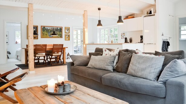 Una sala moderna con un sofá gris, una mesa de comedor de madera y luces colgantes.