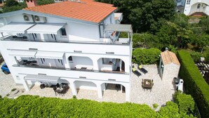 A multi-story white building with a red-tiled roof, balconies, and outdoor seating areas.