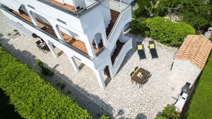 A modern building with a rooftop terrace featuring outdoor seating and a small table.