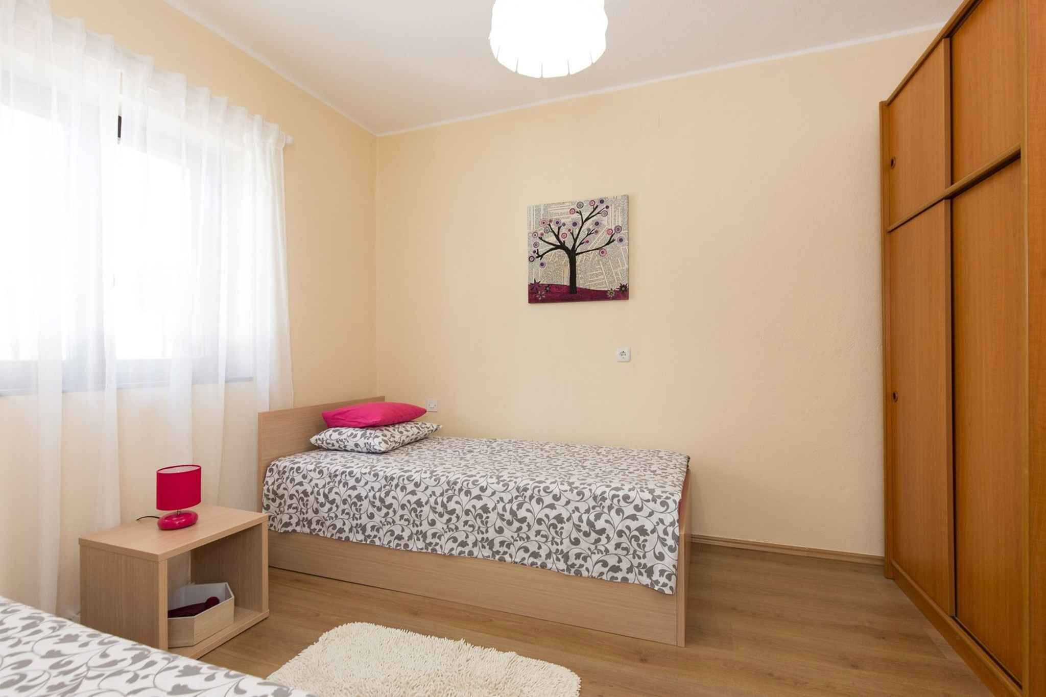 A bedroom with a bed, a nightstand, a wardrobe, and a painting on the wall.