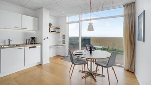 Una cocina moderna con armarios blancos, encimera de madera y un comedor con mesa y sillas redondas.