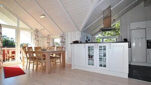 A spacious kitchen with white cabinetry, a dining area with wooden chairs, and a large window providing natural light. - Amazing home in Fanø with WiFi (Fanø)